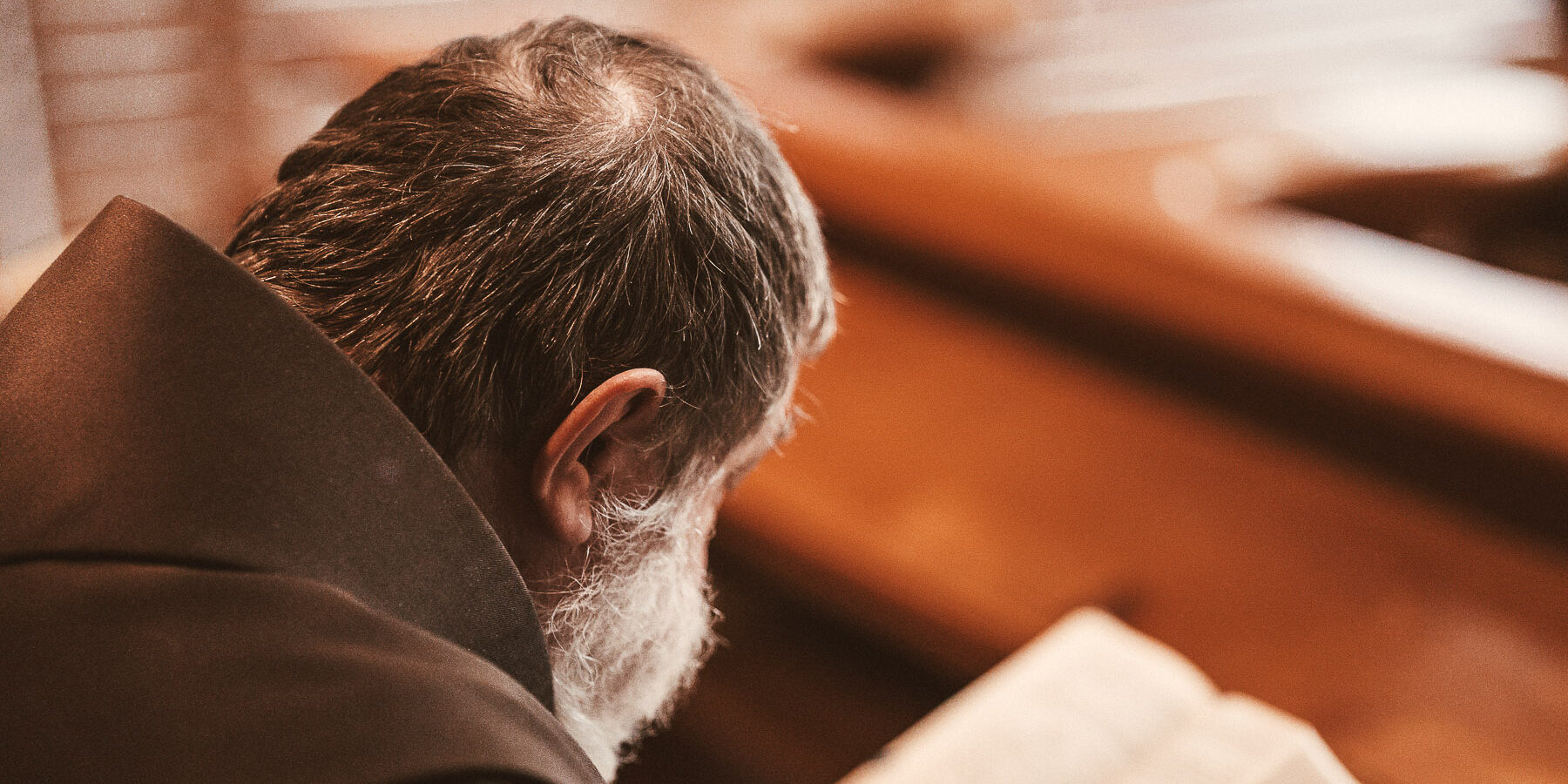 Franziskaner mit Buch ins Gebet vertieft