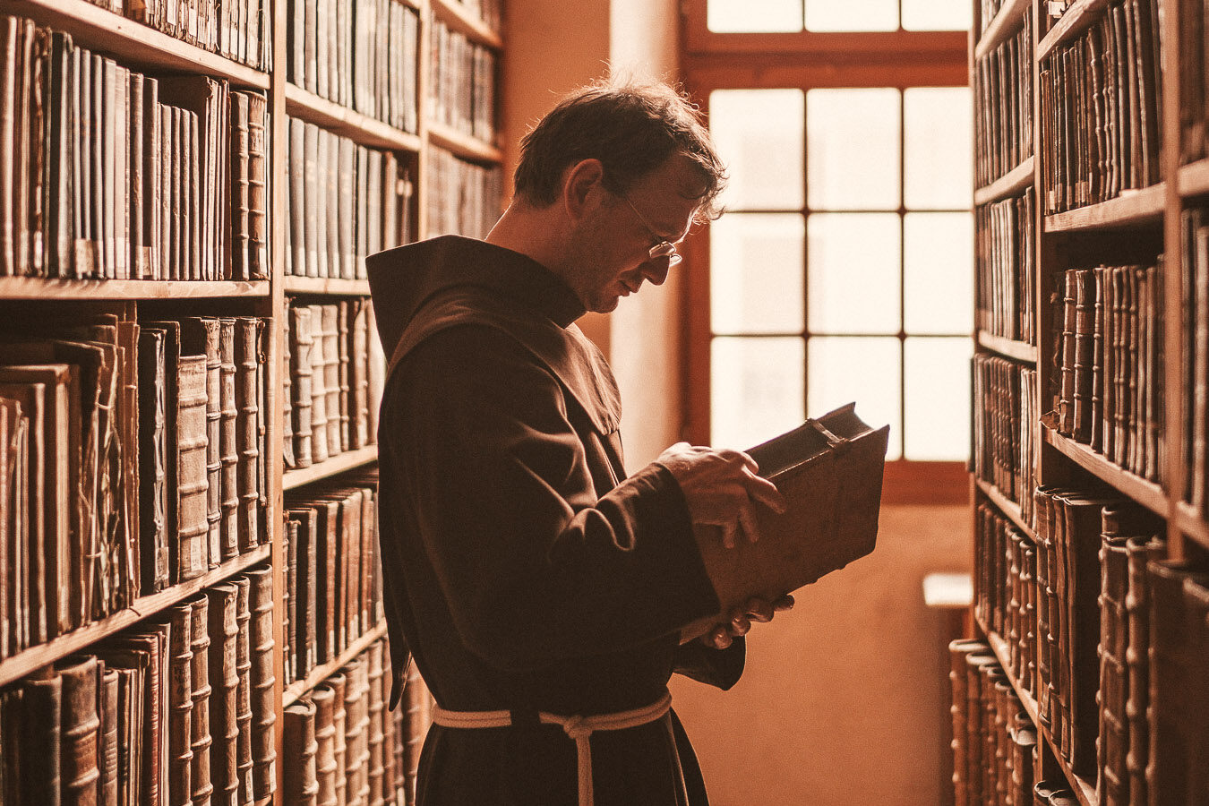 Franziskaner ließt Buch in Bibliothek