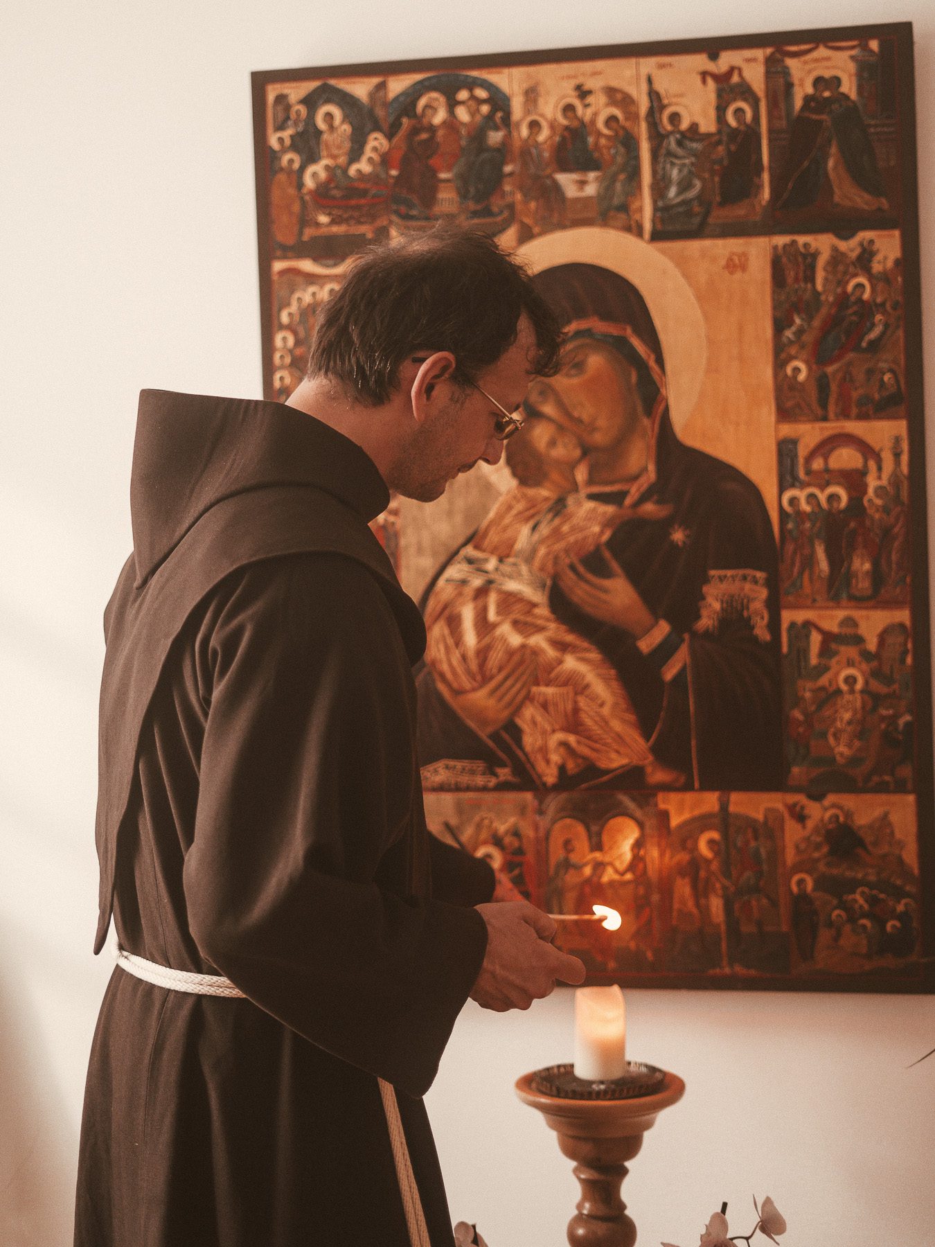 Franziskaner zündet Kerze an