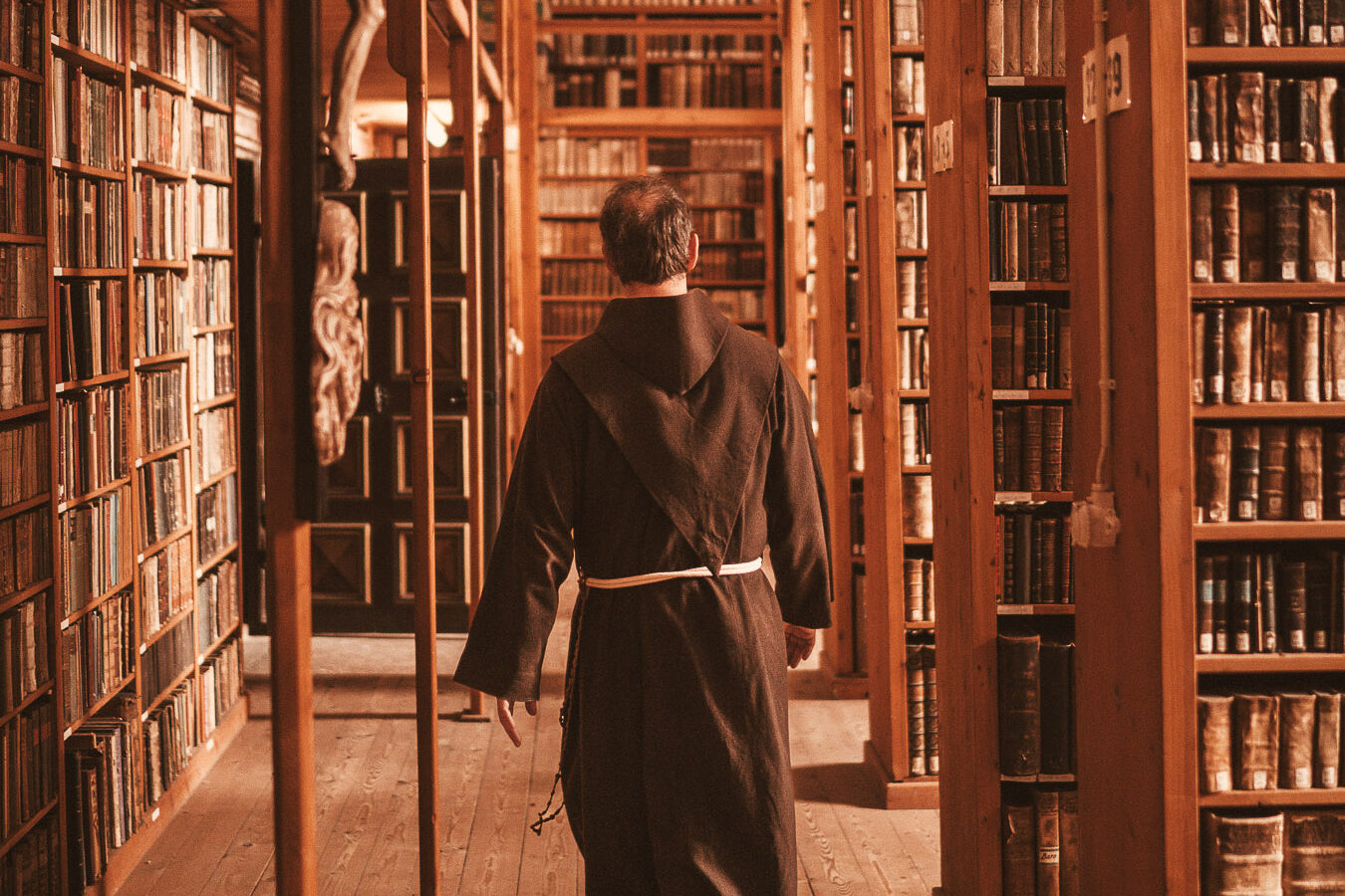 Franziskaner geht durch Bibliothek